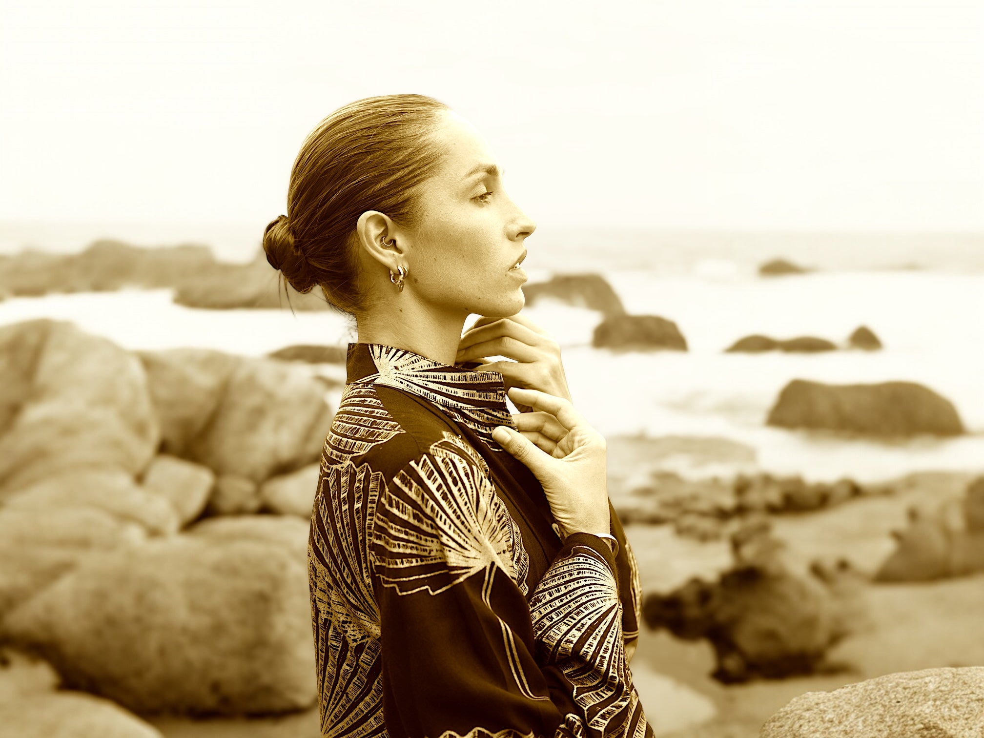 Woman in a patterned dress standing on a rocky beach